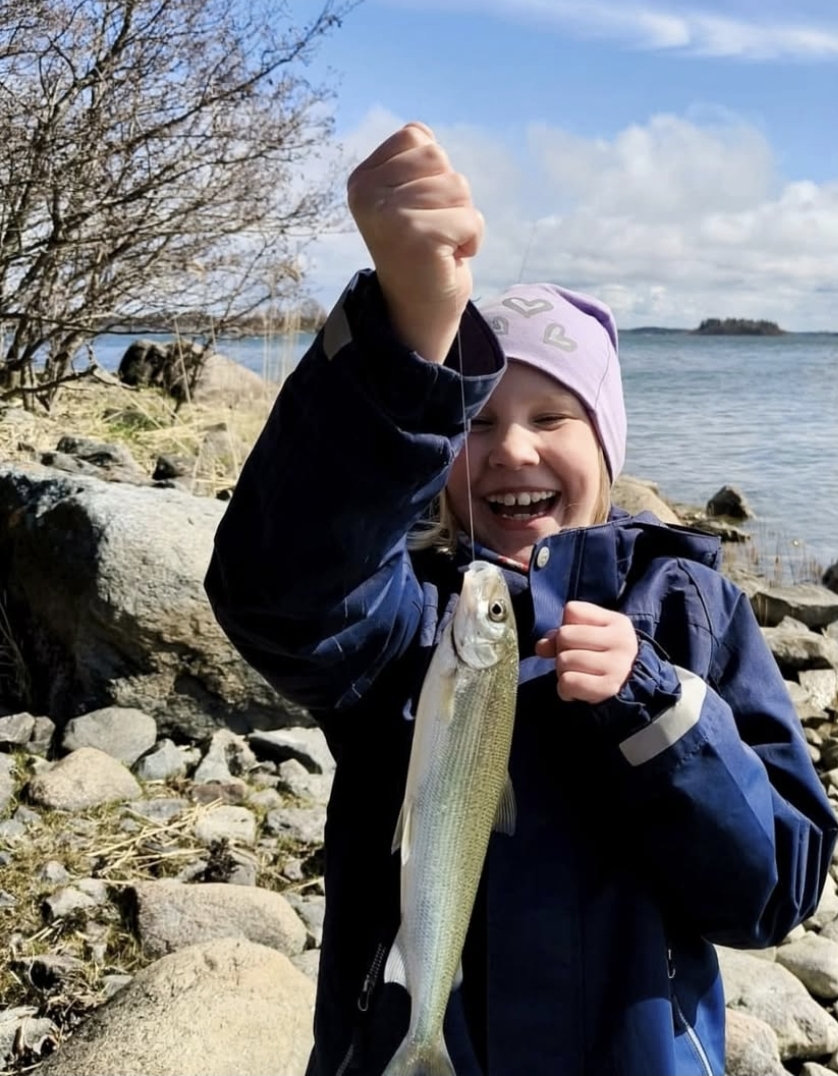 Onnellinen lapsi kalansaaliin kanssa Selkämeren rannalla
