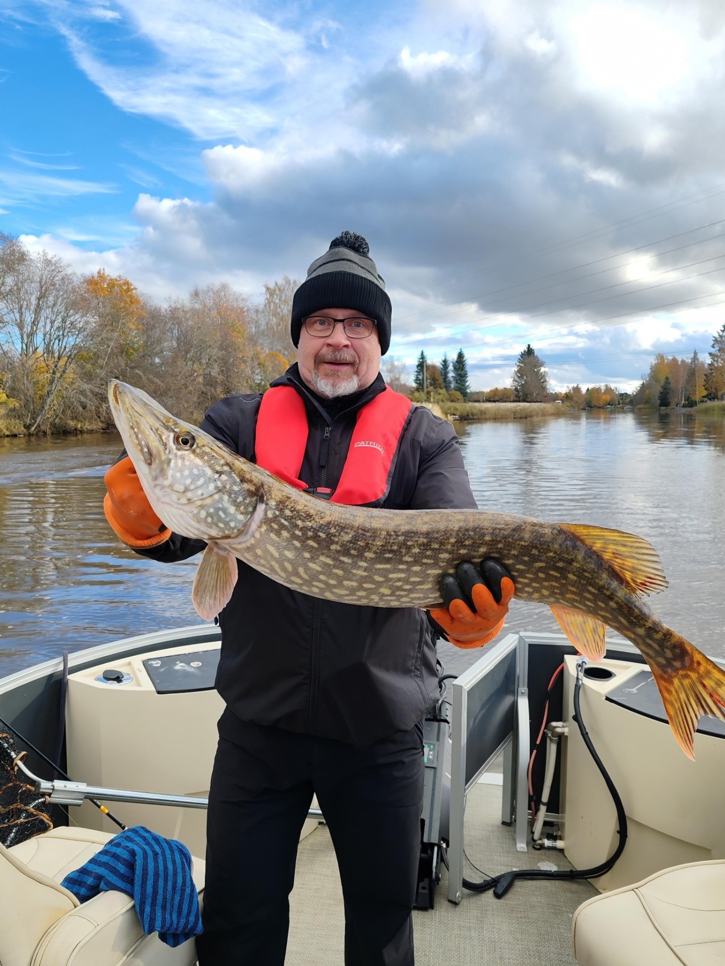 Kalastaja syksyisellä jokimaisemalla isolla hauella